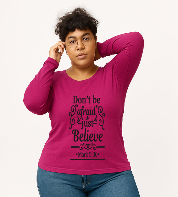 Berry Christian long sleeve t-shirt with “Don’t Be Afraid Just Believe” Mark 5:36 scripture design, worn by woman in glasses and ripped jeans.

