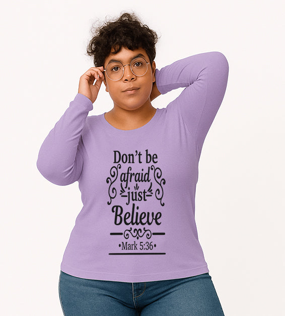 Dark Lavender Christian long sleeve t-shirt with “Don’t Be Afraid Just Believe” Mark 5:36 scripture design, worn by woman in glasses and ripped jeans.

