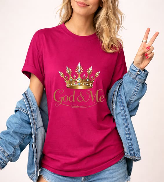Young woman wearing berry/magenta God and Me crown graphic t-shirt with gold design, faith-based Christian apparel,