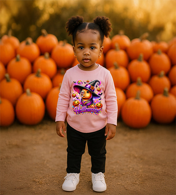 Toddler girl wearing pink Halloween t-shirt with cartoon capybara witch design, pumpkins, sparkles, and the word Halloween in bold lettering