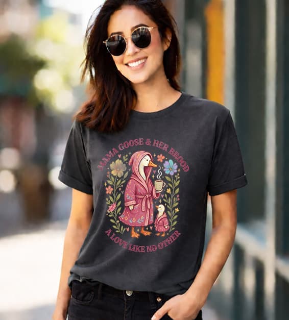 woman wearing dark grey t-shirt with mama goose and baby goose illustration and text mama goose and her brood a love like no other