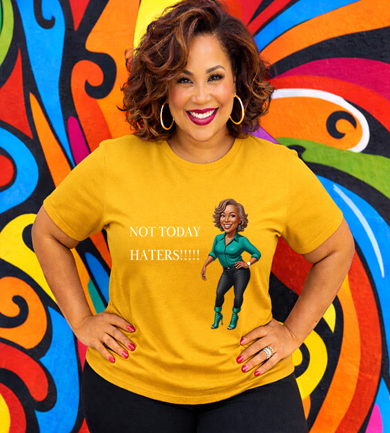 Woman wearing a gold Bella Canvas t-shirt with motivational “Not Today Haters” graphic design in front of colorful mural background.