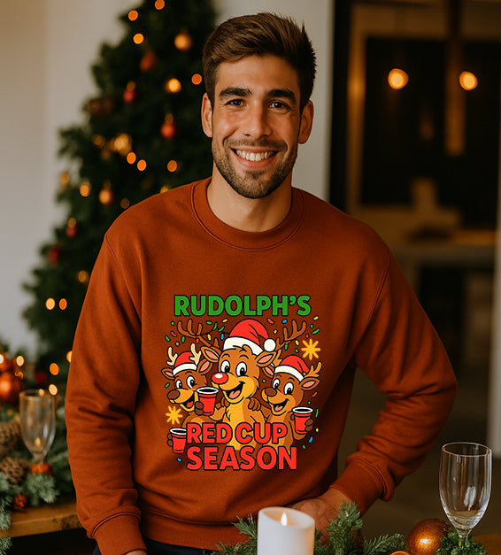 Man wearing a autumn Christmas sweatshirt with a festive cartoon reindeer design and the text “Rudolph’s Red Cup Season” in bright holiday colors.