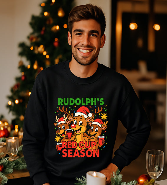 Man wearing a black Christmas sweatshirt with a festive cartoon reindeer design and the text “Rudolph’s Red Cup Season” in bright holiday colors.