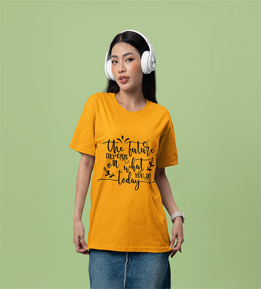 A woman wearing headphones and a gold/sunflower color T-shirt that reads “The Future Depends on What You Do Today” in a cursive black font, posing against a soft green background.